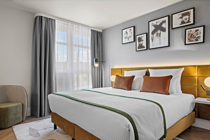 Hotelzimmer mit Doppelbett in Weiß, Grau und Ocker