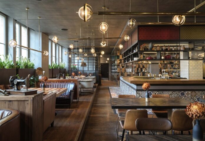 Restaurant mit Holztischen, Ledersitzen und runden Hängeleuchten mit Golddetails