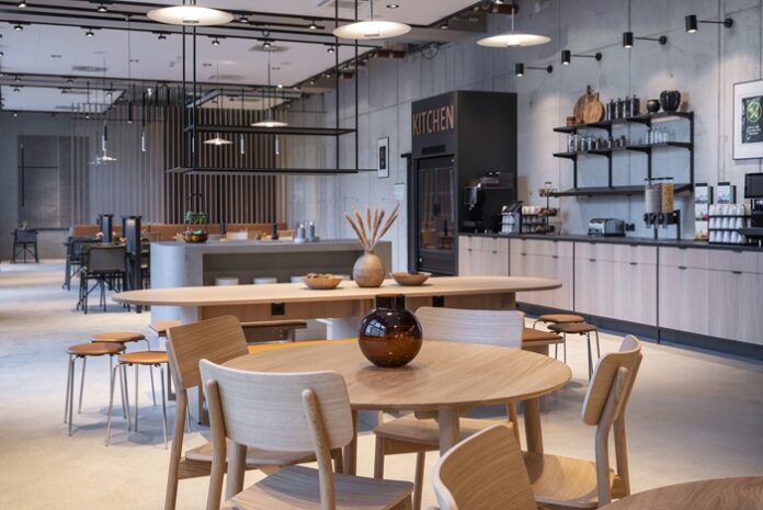 Helle Holztische und -stühle vor hellgrauem Ambiente im Industrial Look