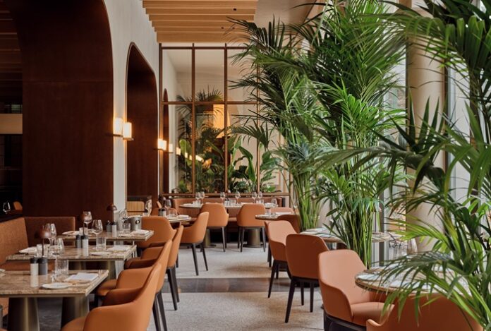 Restaurantbereich mit raumhohen Fenstern und Palmen