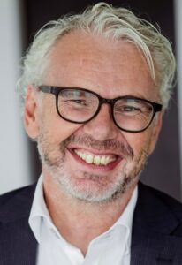 Grauhaariger Mann mit Bart und dunkler Brille