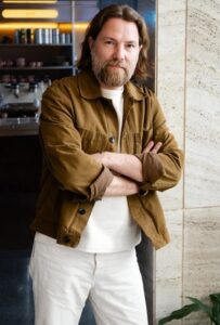 Bärtiger Mann in heller Hose und karamellfarbener lässiger Jacke